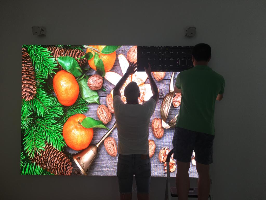 Professional technicians installing outdoor LED screen cabinet modules on a video wall structure